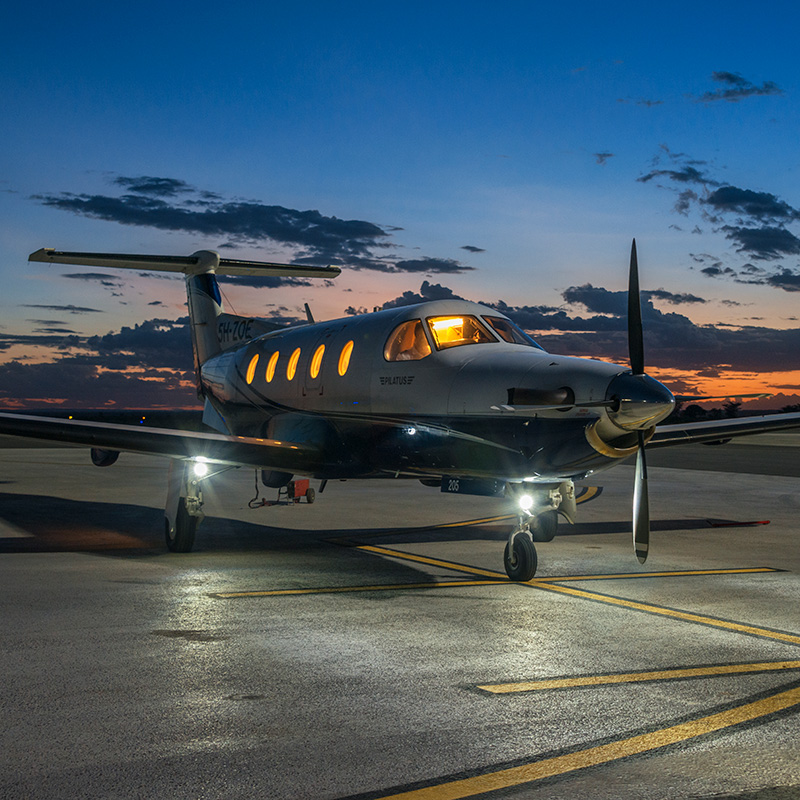 A Pilatus PC-12 aircraft on a runway at dusk